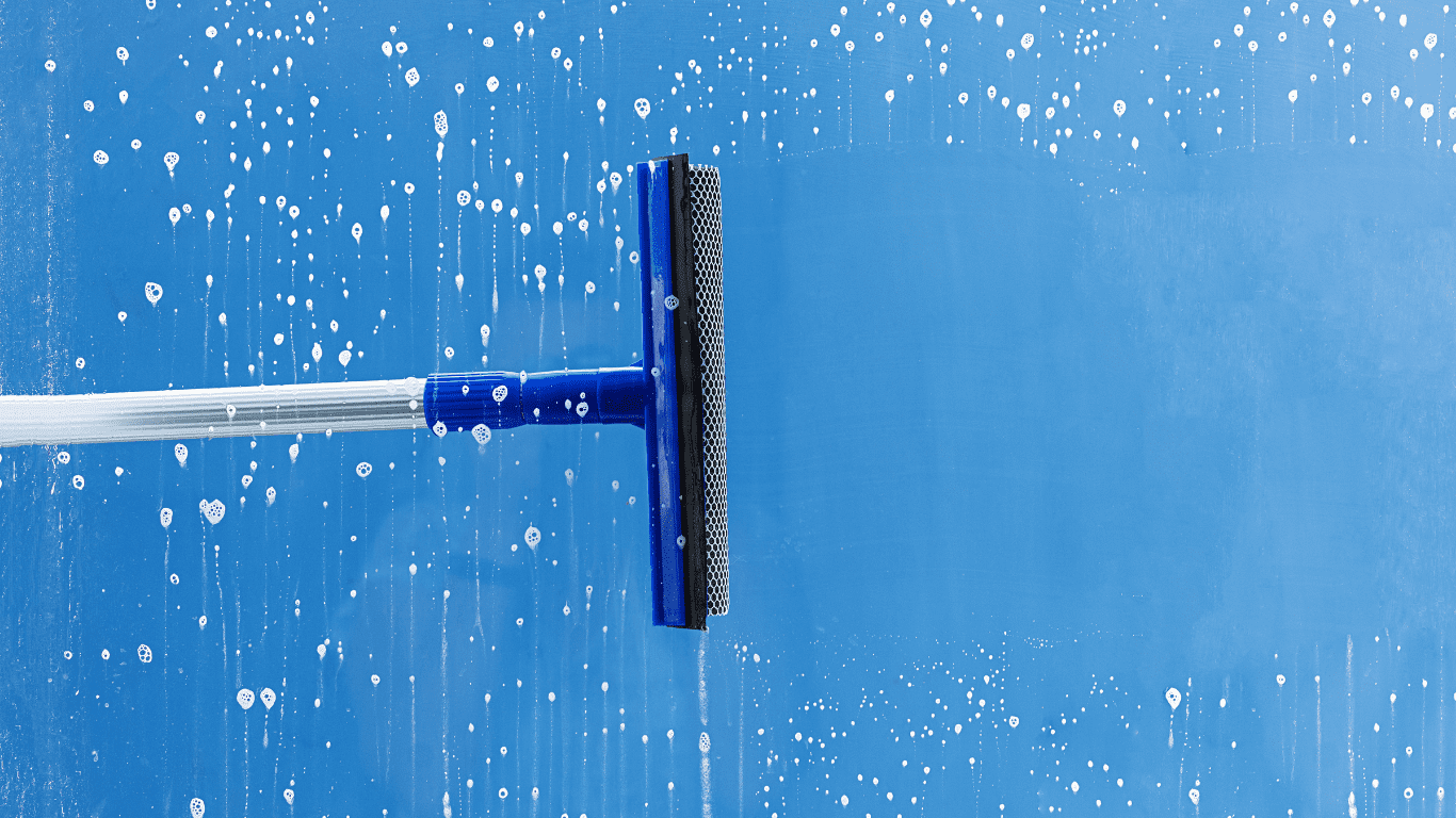 Squeegee cleaning a blue surface with soap bubbles, representing professional cleaning services by Deep Clean King.