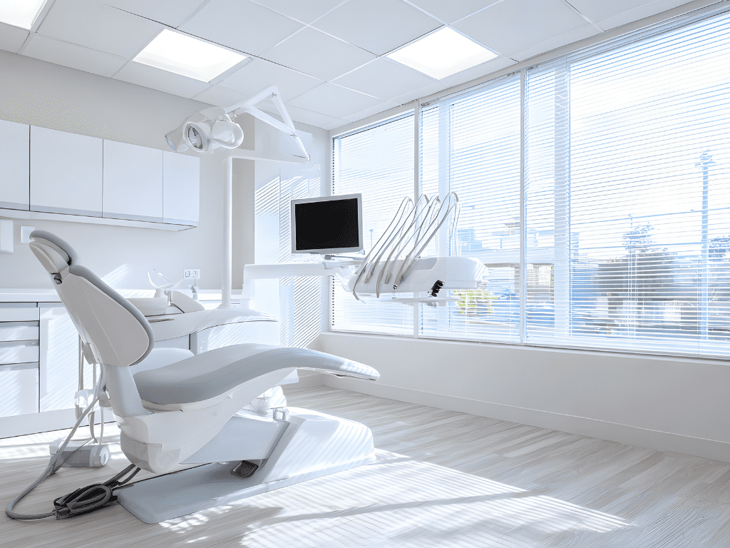Modern dental treatment room with dental chair, equipment, and natural light from large windows, emphasizing a clean and hygienic environment for medical and aged care cleaning services.
