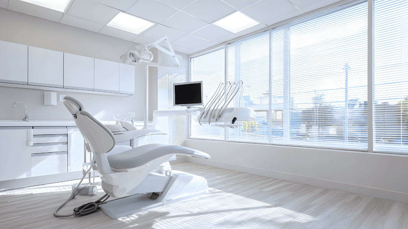 Dental clinic interior with modern dental chair, monitor, and bright natural light through large windows, emphasizing cleanliness and professionalism in commercial cleaning services.