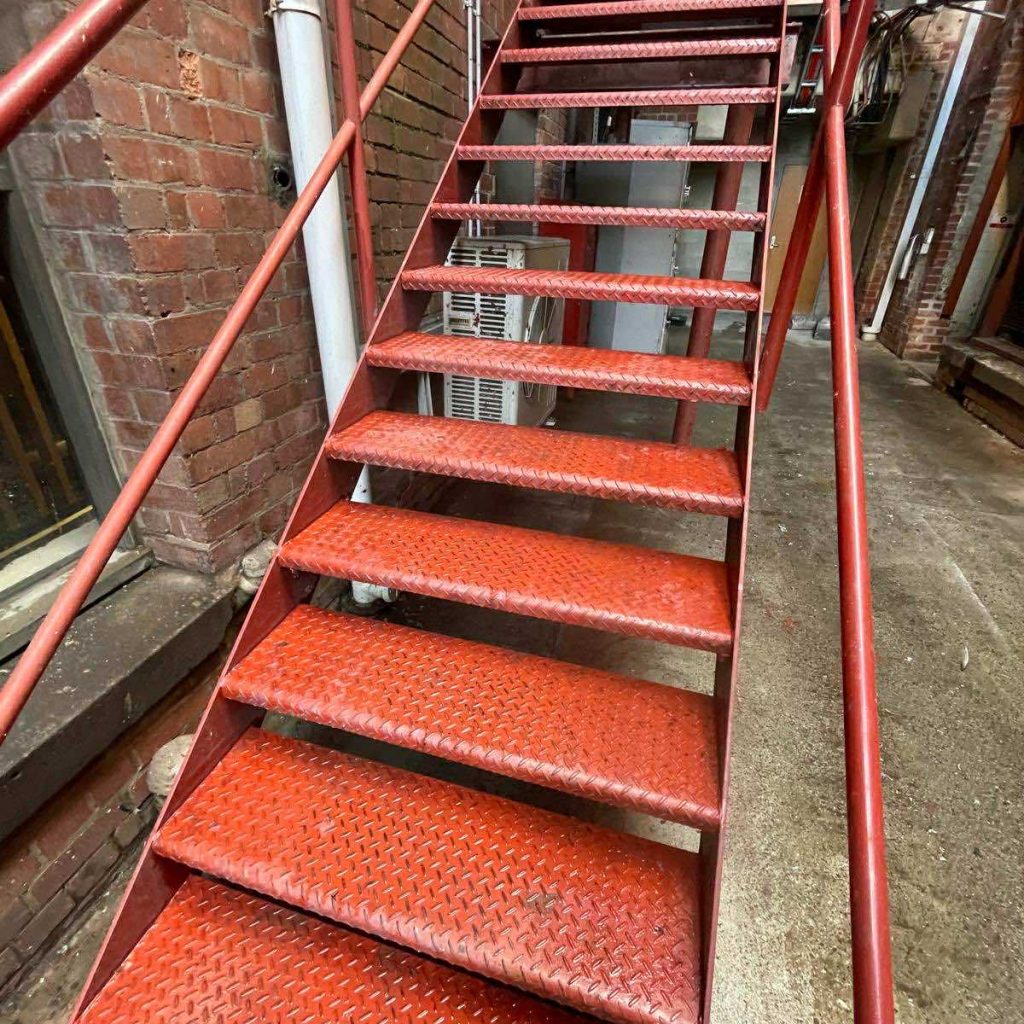 Red metal stairwell with diamond-patterned steps, showcasing post-construction cleaning readiness in a Melbourne property.